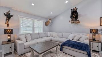 A modern living room with a sectional sofa, a coffee table, and decorative animal mounts on the walls.