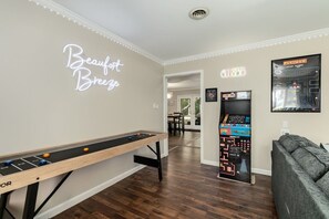 Ein Zimmer mit einem Kicker, einem Kicker mit einer Neonreklame und einem Sofa.