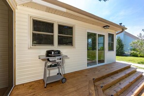 Ein Haus mit einer Veranda und Grill, auf einem Wagen, sowie einer Glasschiebetür.