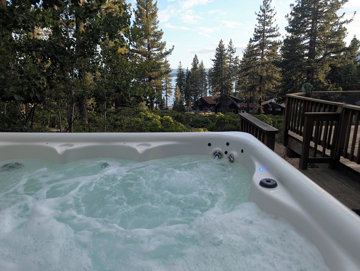 Een hottub omringd door bomen en een houten terras.