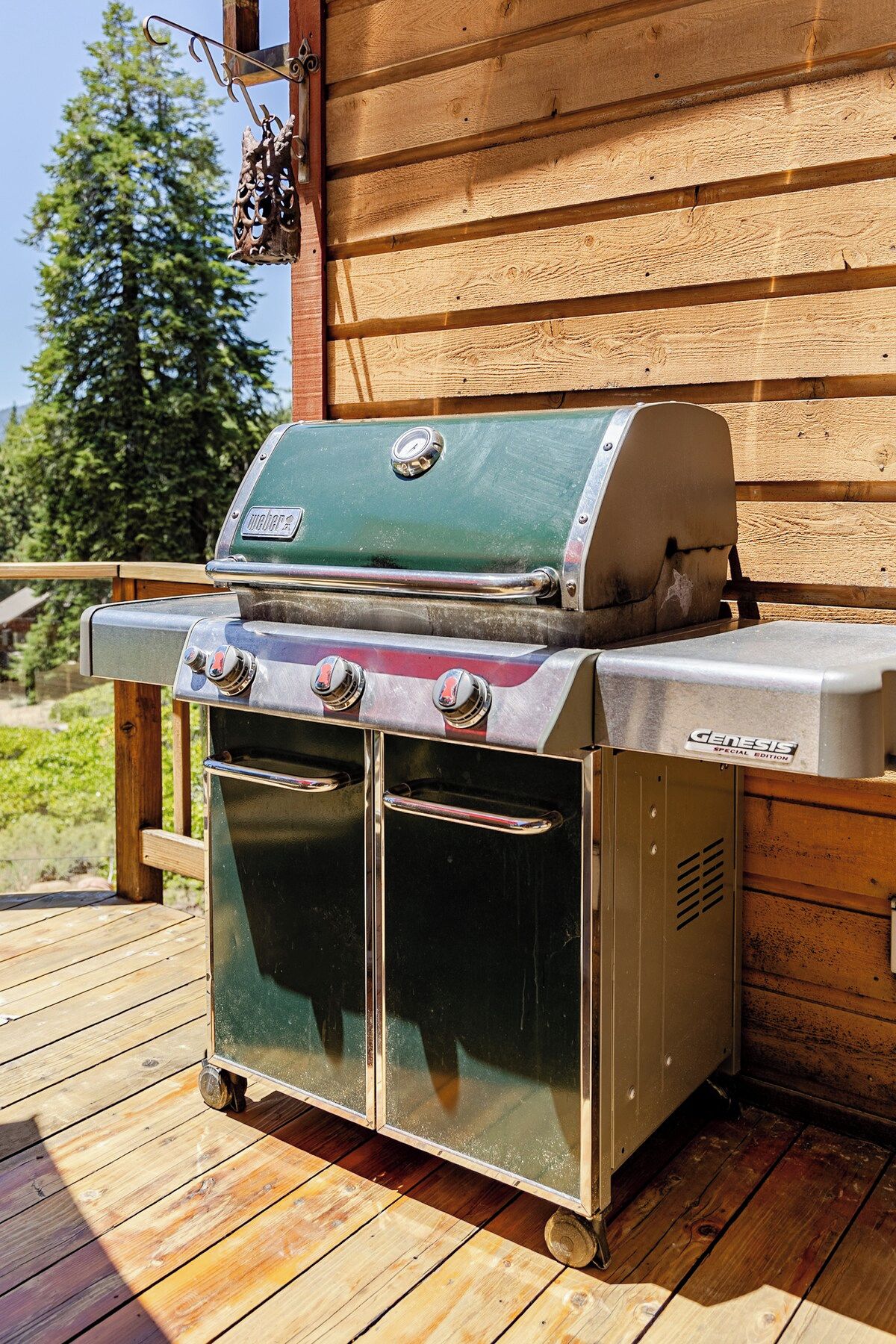 Un barbecue portable de la série spéciale Genesis, doté d’un brûleur latéral et d’un four, installé sur une terrasse en bois.
