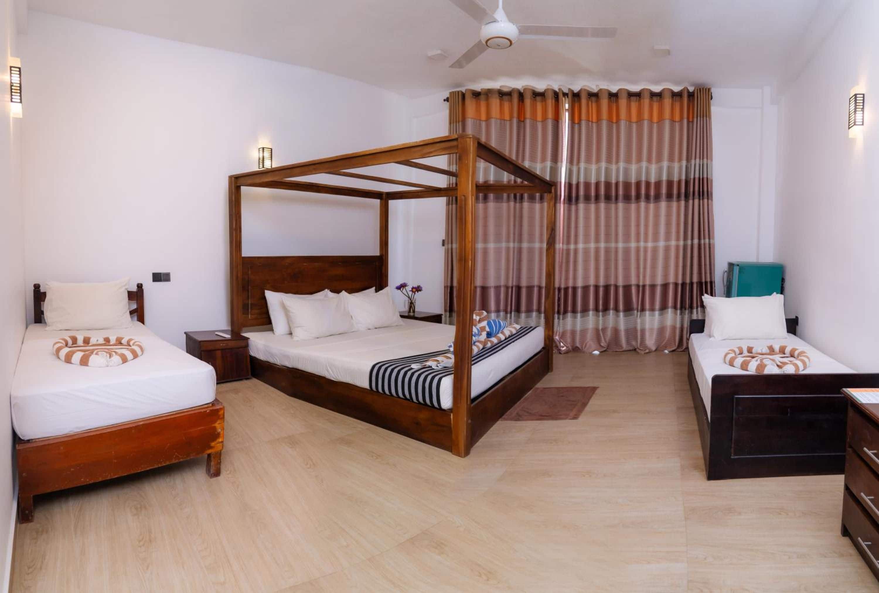 A bedroom with a four-poster bed, two single beds, a desk, and a chair.