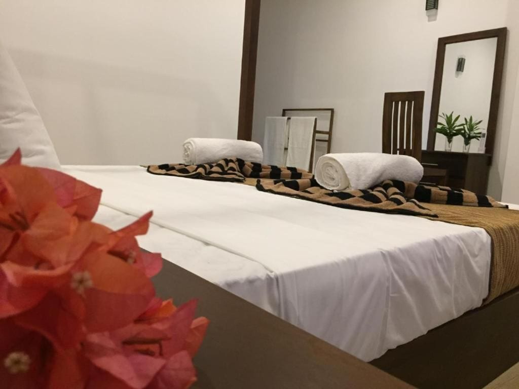 A hotel room with a bed, towels, a mirror, and a potted plant.