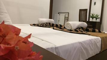 A hotel room with a bed, towels, a mirror, and a potted plant.