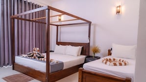 A room with a four-poster bed, a smaller single bed, and a nightstand with a lamp. - Bay Hiriketiya (Dikwella)