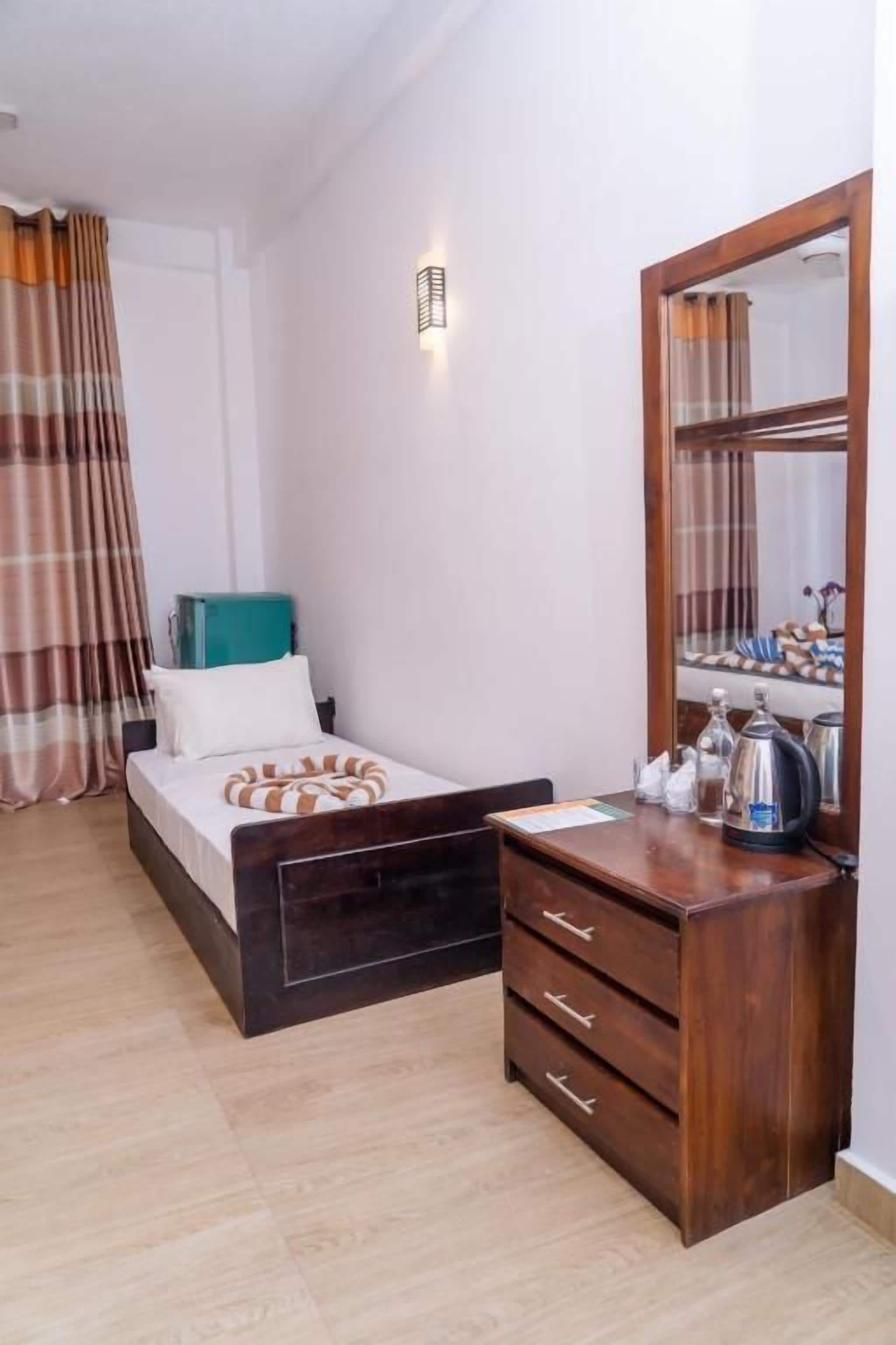 Un dormitorio con una cama, un aparador de madera, un espejo y una mesita de noche.