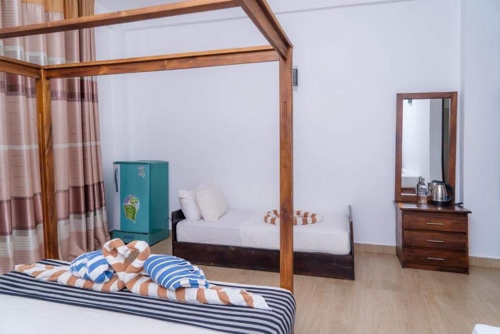 A bedroom with a four-poster bed, a wooden dresser, a mirror, and a green cabinet.