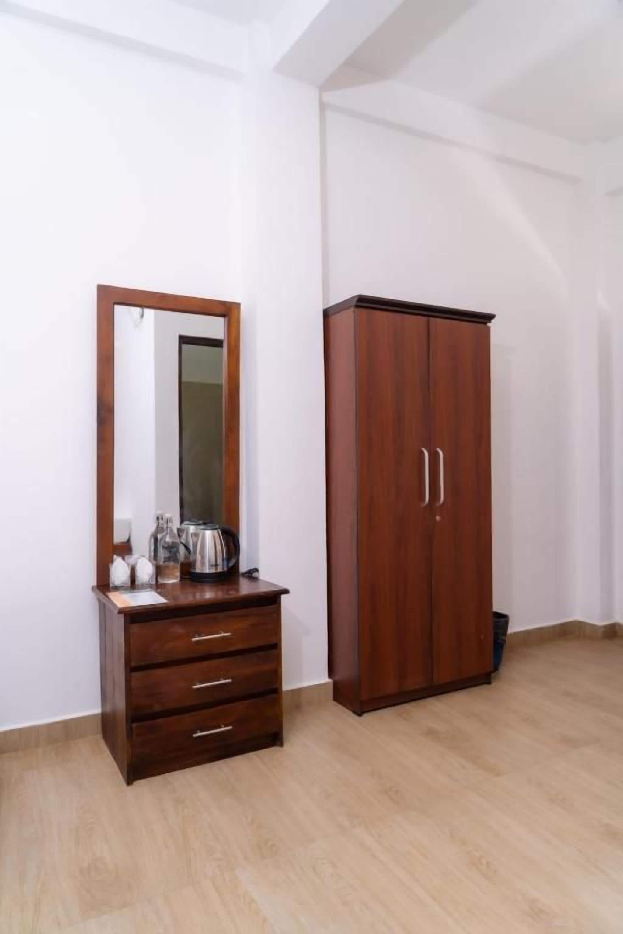 Una habitación con un armario de madera, un espejo y un pequeño aparador de madera.