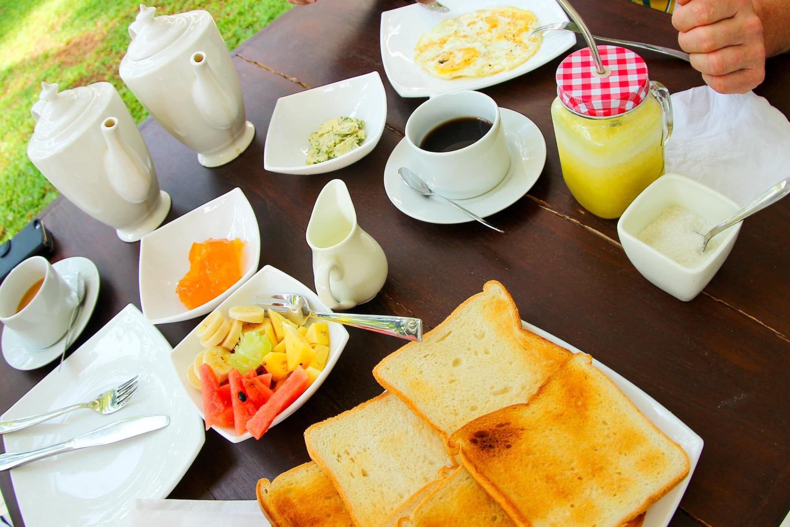 Una mesa de desayuno con diversos alimentos y bebidas, como tostadas, fruta y una taza de café.