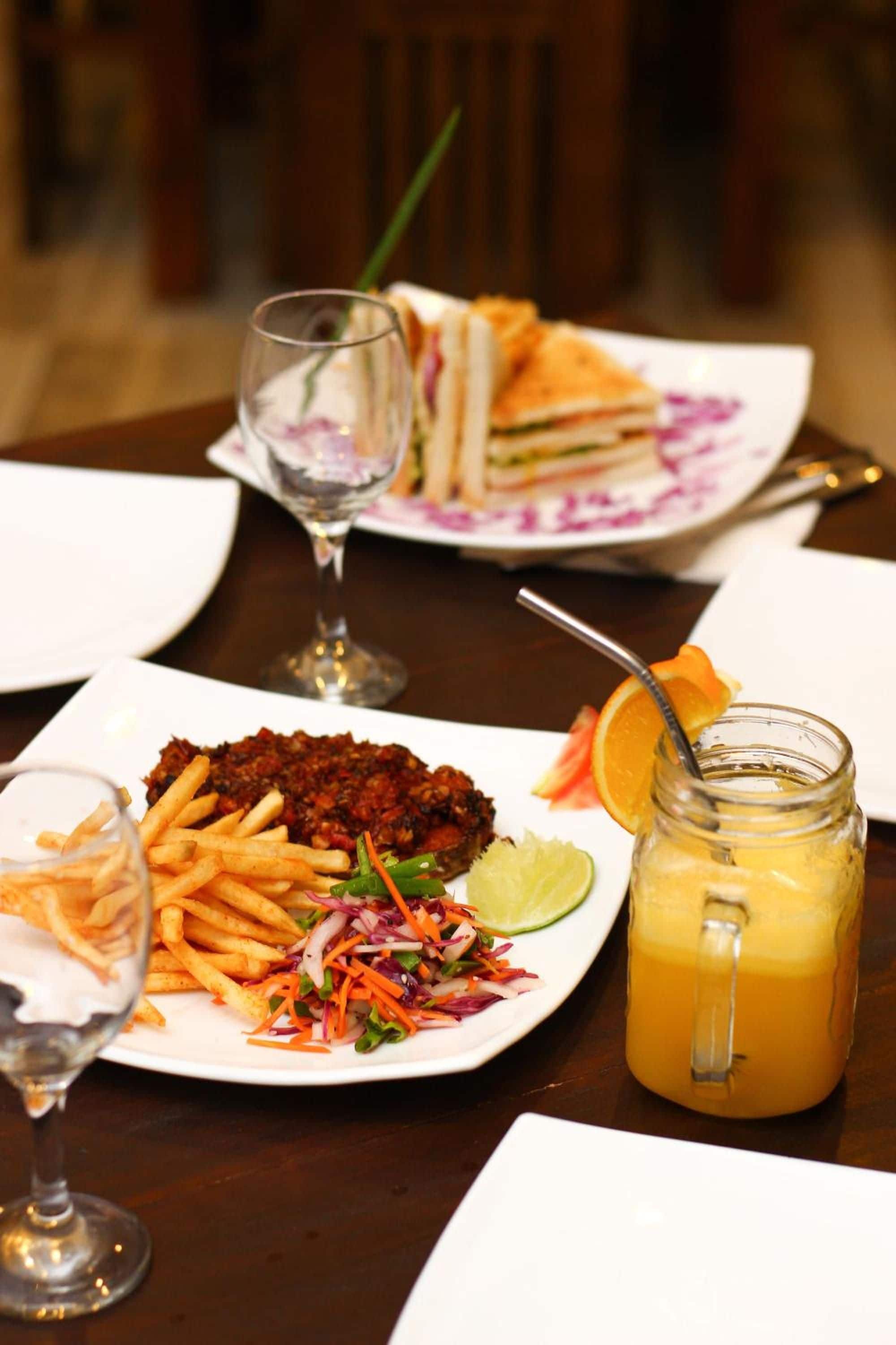 A dining table with plates of food, a glass of juice, and a glass of water.