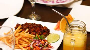 A dining table with plates of food, a glass of juice, and a glass of water.