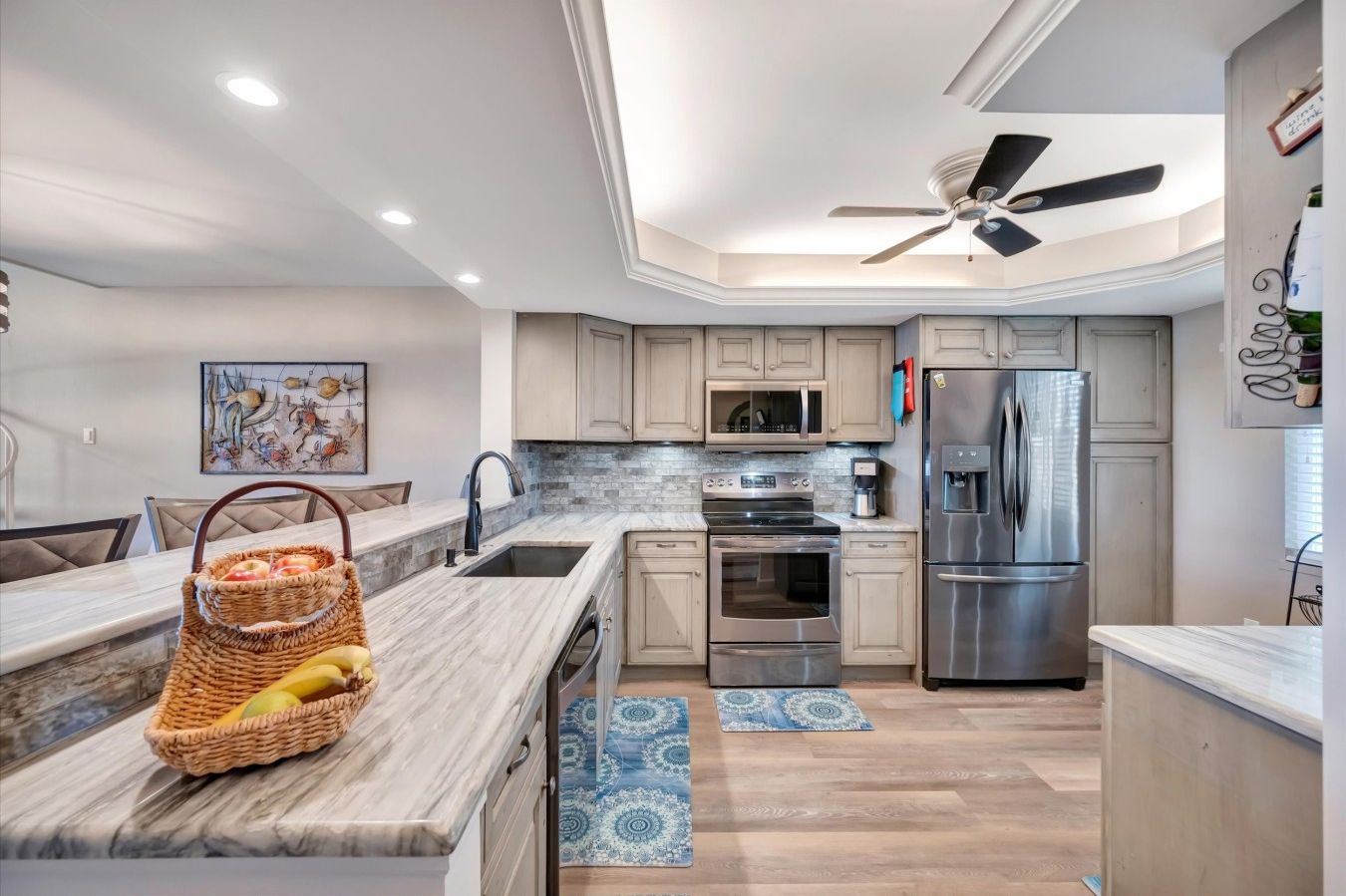 Una cocina moderna con una isla central, electrodomésticos de acero inoxidable y un ventilador de techo.