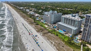 Ein Küstenhotel mit mehreren Hochhäusern, einem Strand und einem Poolbereich.