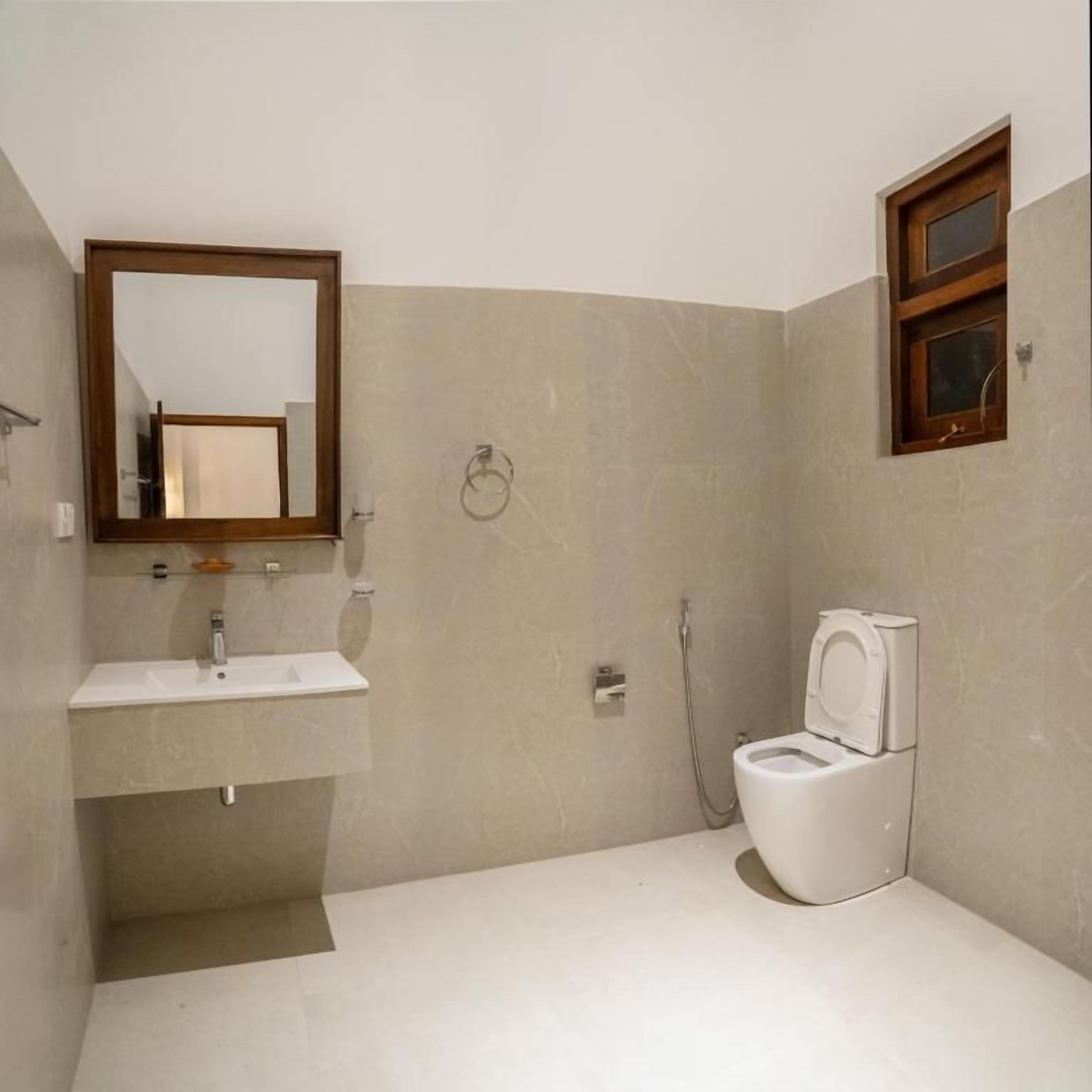 Un baño con lavamanos, espejo, inodoro y ducha.