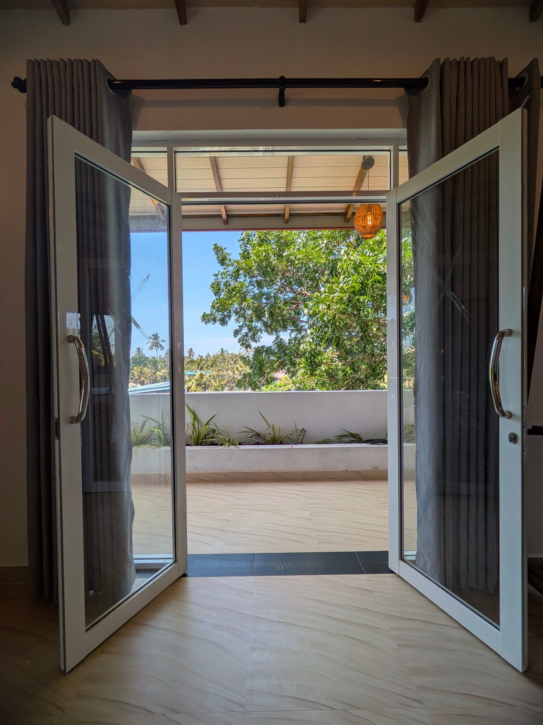 Habitación con puerta de vidrio corrediza que da a un espacio exterior con vistas a vegetación y un cielo despejado.