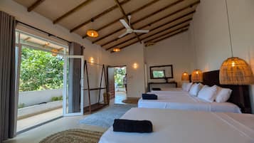 Habitación de hotel con dos camas, un ventilador de techo y un amplio ventanal con vistas a la vegetación.