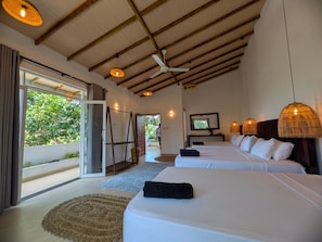 A hotel room with two beds, a ceiling fan, and a large window with a view of greenery.