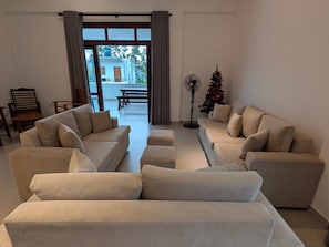 A living room with a sofa set, a standing fan, and a Christmas tree.