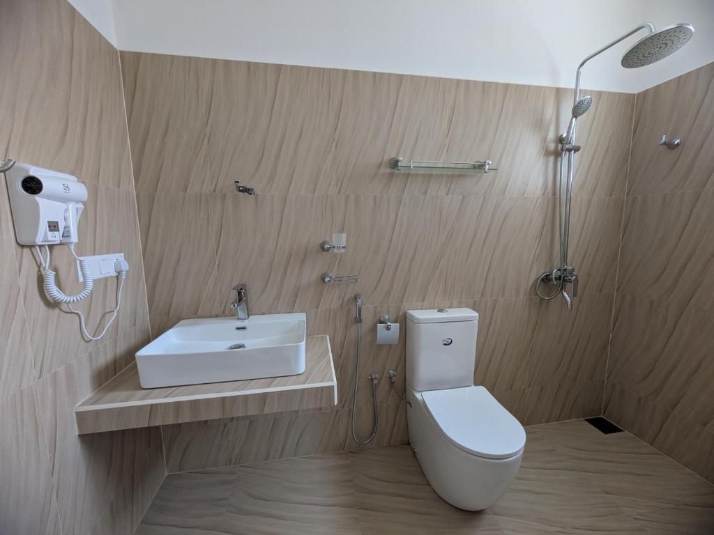 A modern bathroom with a white sink, toilet, and shower.