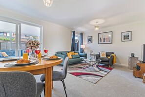 Ein modernes Wohnzimmer mit Essbereich, einer Sofagarnitur und einem Fernseher.