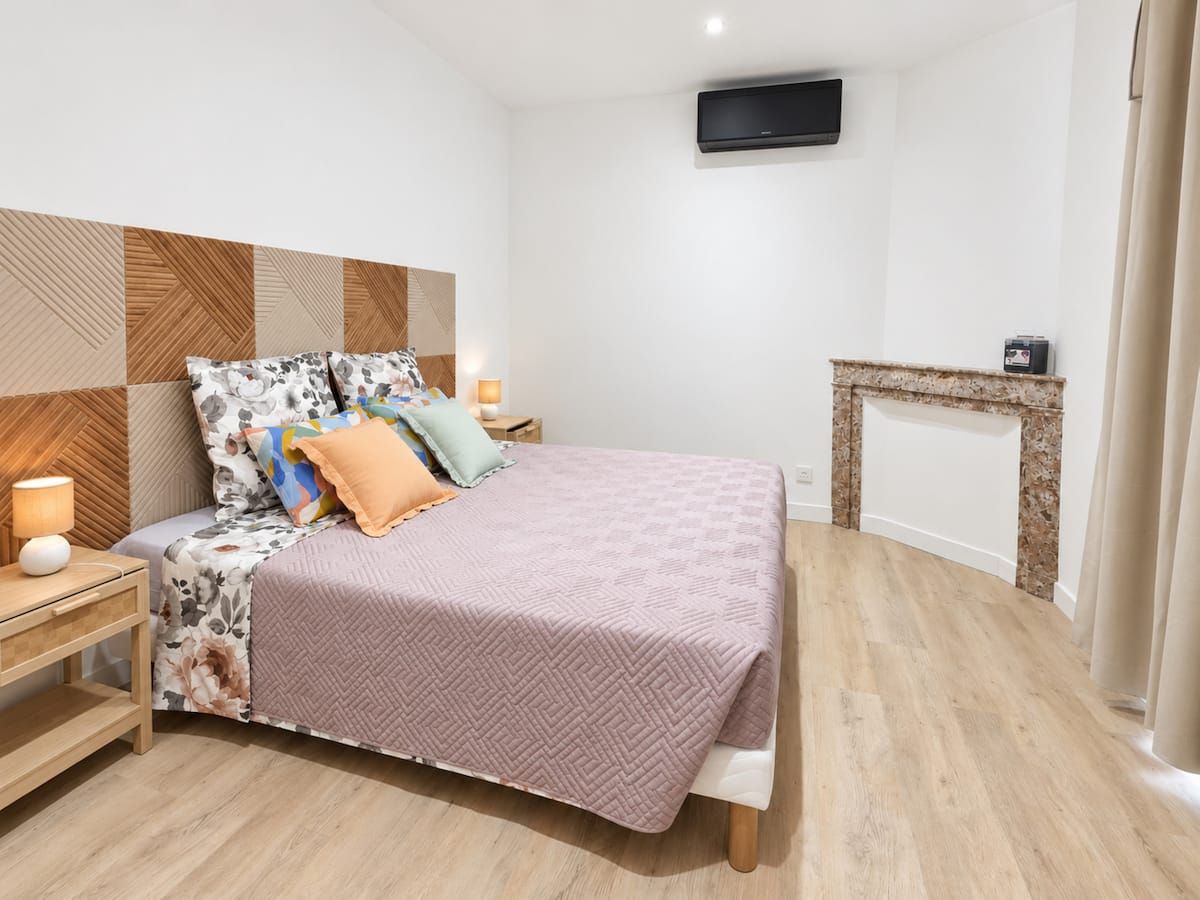 Une chambre à coucher avec un lit, des tables de chevet, un téléviseur et une cheminée.