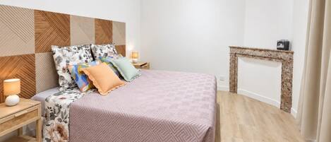 Une chambre à coucher avec un lit, des tables de chevet, un téléviseur et une cheminée.