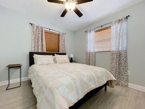 Une chambre à coucher avec un lit, un ventilateur de plafond et des rideaux.