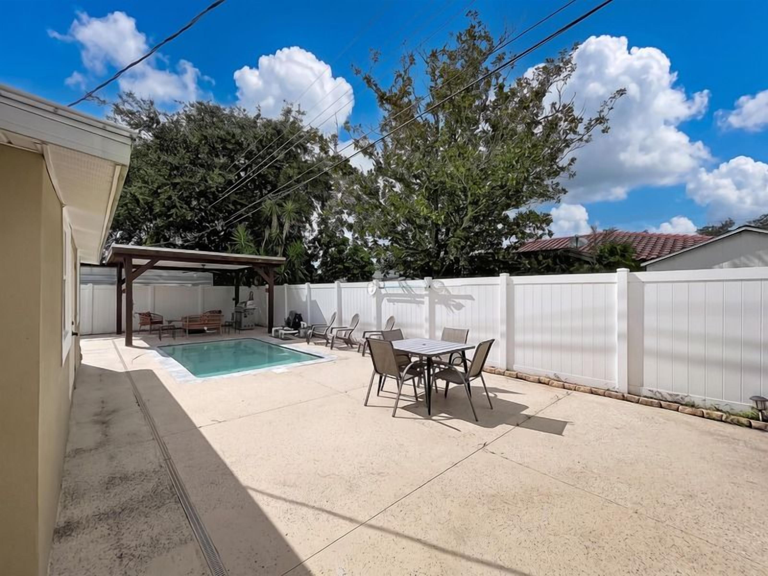 Un jardin avec une piscine, des meubles de patio et un espace salon abrité.