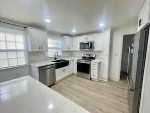 A modern kitchen with white cabinets, stainless steel appliances, and a light wood floor. - HPU Perfect New House (High Point)