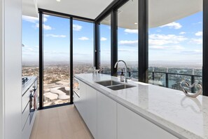A modern kitchen with a large window, a sink, and a heart-shaped decoration. - Luxury 2BR with Panoramic Gold Coast Views (Broadbeach)