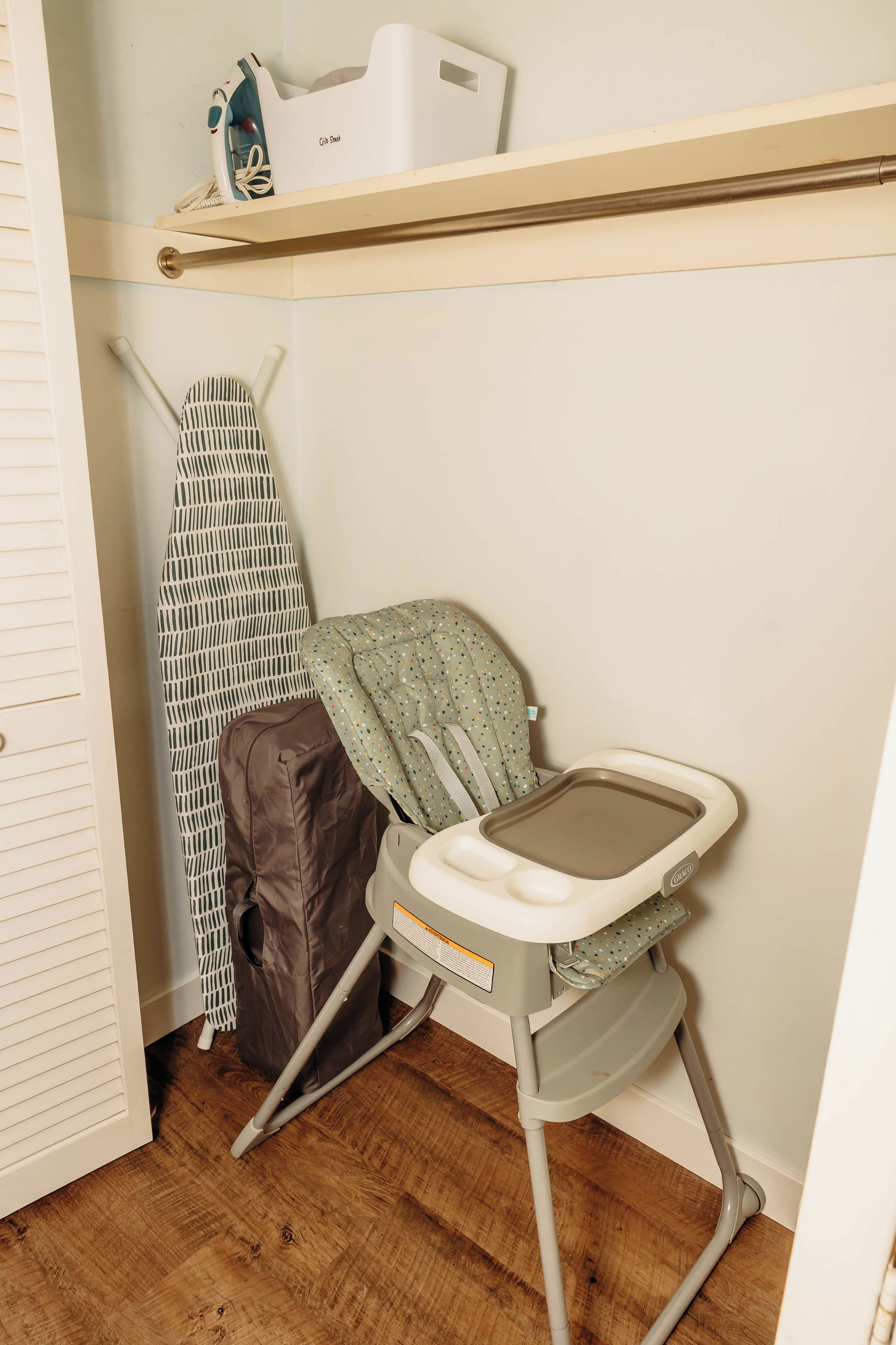Un cambiador para bebés con una trona, una plancha plegable y un estante con productos para bebé.