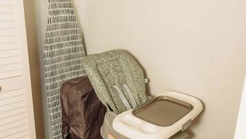 Un cambiador para bebés con una trona, una plancha plegable y un estante con productos para bebé.