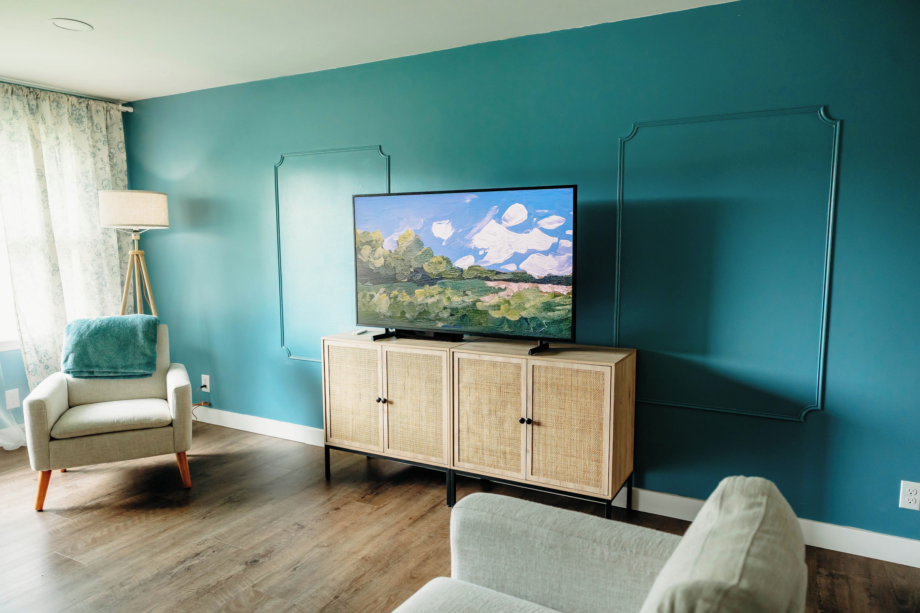 Una sala de estar con televisor sobre un mueble de madera, una lámpara y un sillón.