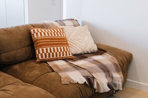 Ein braunes Sofa mit zwei Zierkissen und einer Decke.