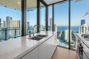Eine moderne Küche mit einem großen Fenster, einer Spüle und Blick auf die Stadt.