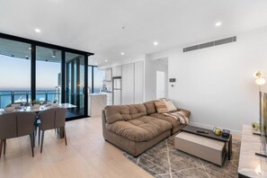 Ein modernes Wohnzimmer mit einer Couch, einem Esstisch und Blick auf die Stadt.