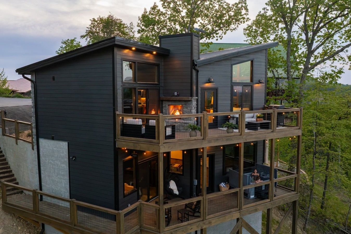 A multi-level cabin with a fireplace, outdoor seating, and a deck.