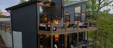 A multi-level cabin with a fireplace, outdoor seating, and a deck.