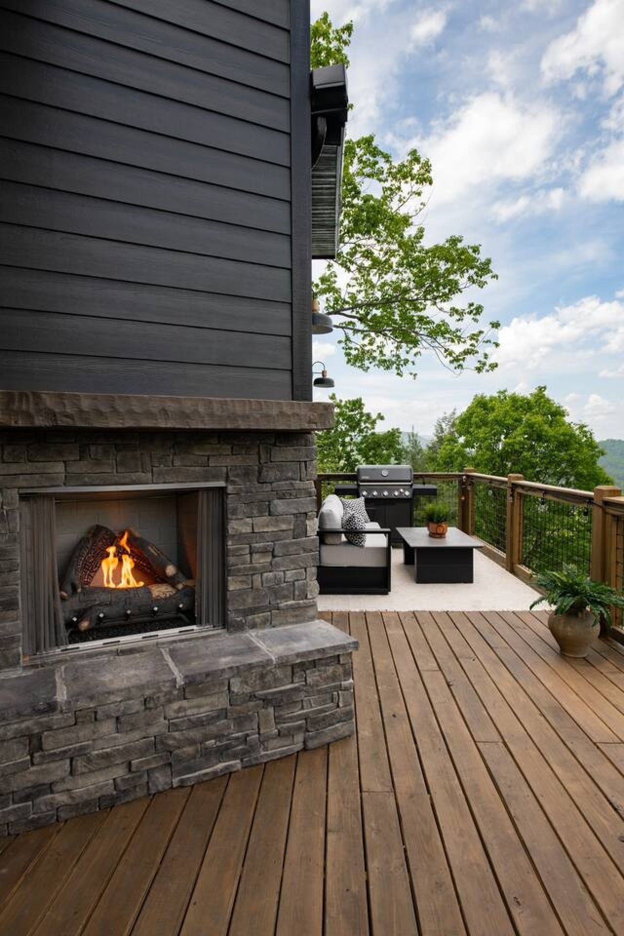 Eine Terrasse mit Kamin aus Stein, Sitzgelegenheit und Blick auf die umliegende Landschaft.