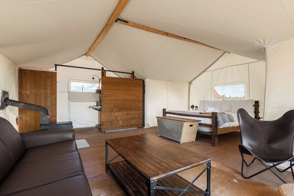 A tented accommodation with a bed, seating area, and a kitchenette. - Under Canvas Santa Fe (Lamy)