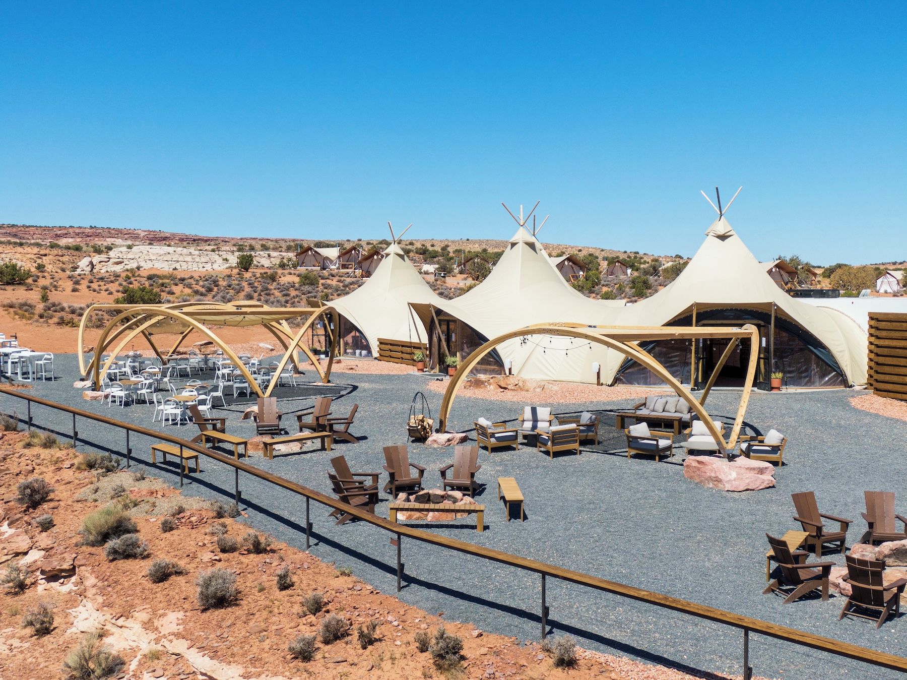 A desert resort with teepees, outdoor seating, and a gravel path.