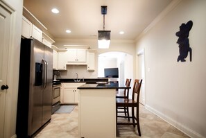 A modern kitchen with a central island, stainless steel appliances, and a dining area with chairs.