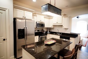 A modern kitchen with stainless steel appliances, white cabinetry, and a granite countertop.