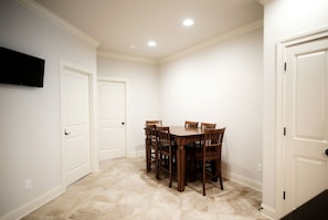 A dining area with a table and chairs, white walls, and a tiled floor.