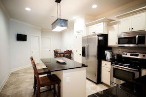 A modern kitchen with a central island, stainless steel appliances, and a dining area with chairs.