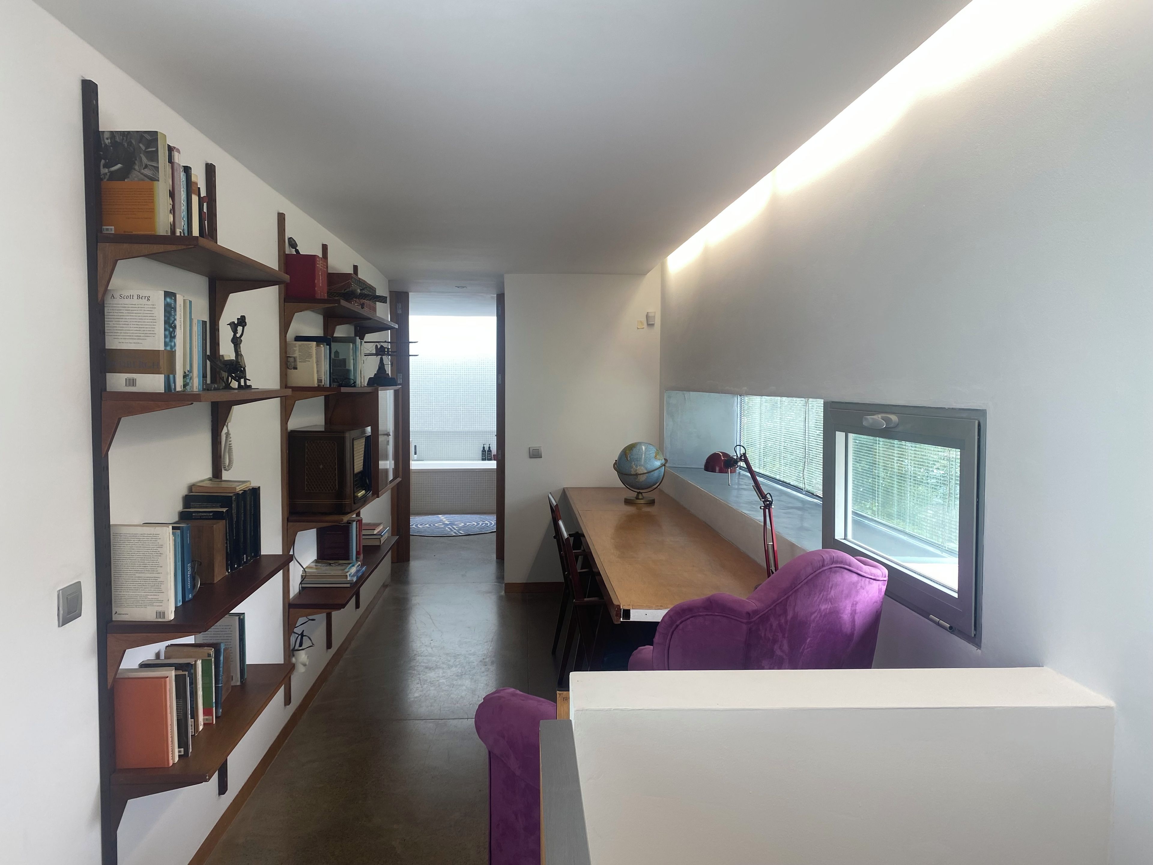Een studeerkamer met een bureau, boekenkasten, een wereldbol en een raam met jaloezieën.