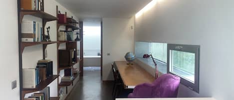 A study room with a desk, bookshelves, a globe, and a window with blinds.
