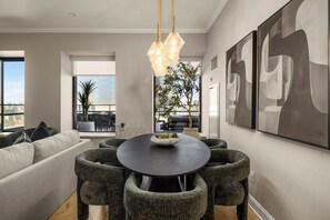 Un área de comedor moderna con una mesa redonda, sillas tapizadas en gris y una lámpara colgante.