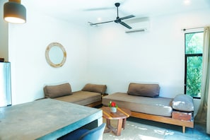 A modern living room with a sofa, a dining table, and a ceiling fan. - Fresh Reno, 5 Min to Beach: Private Compound for Groups of 15 (Nosara)