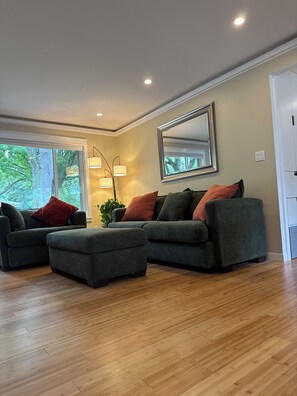 A modern living room with a sectional sofa, a matching ottoman, and a floor lamp.